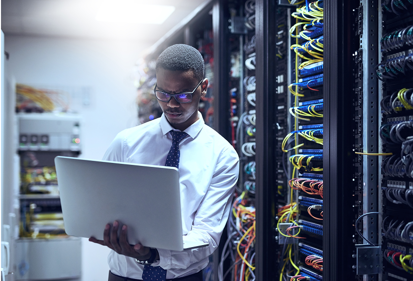 Man working on laptop in server room.