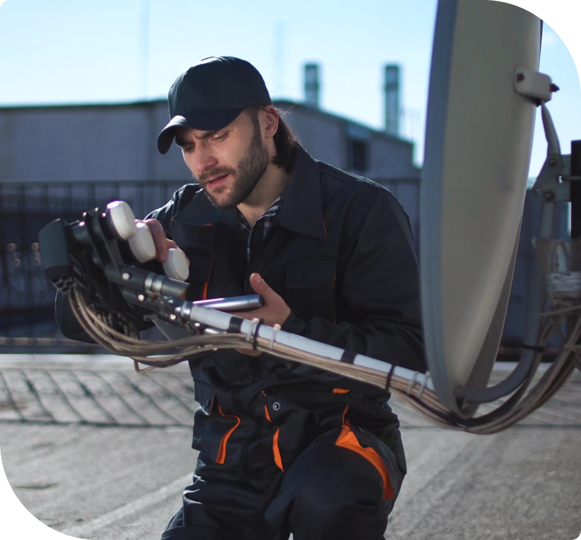Technician adjusting satellite dish on rooftop.